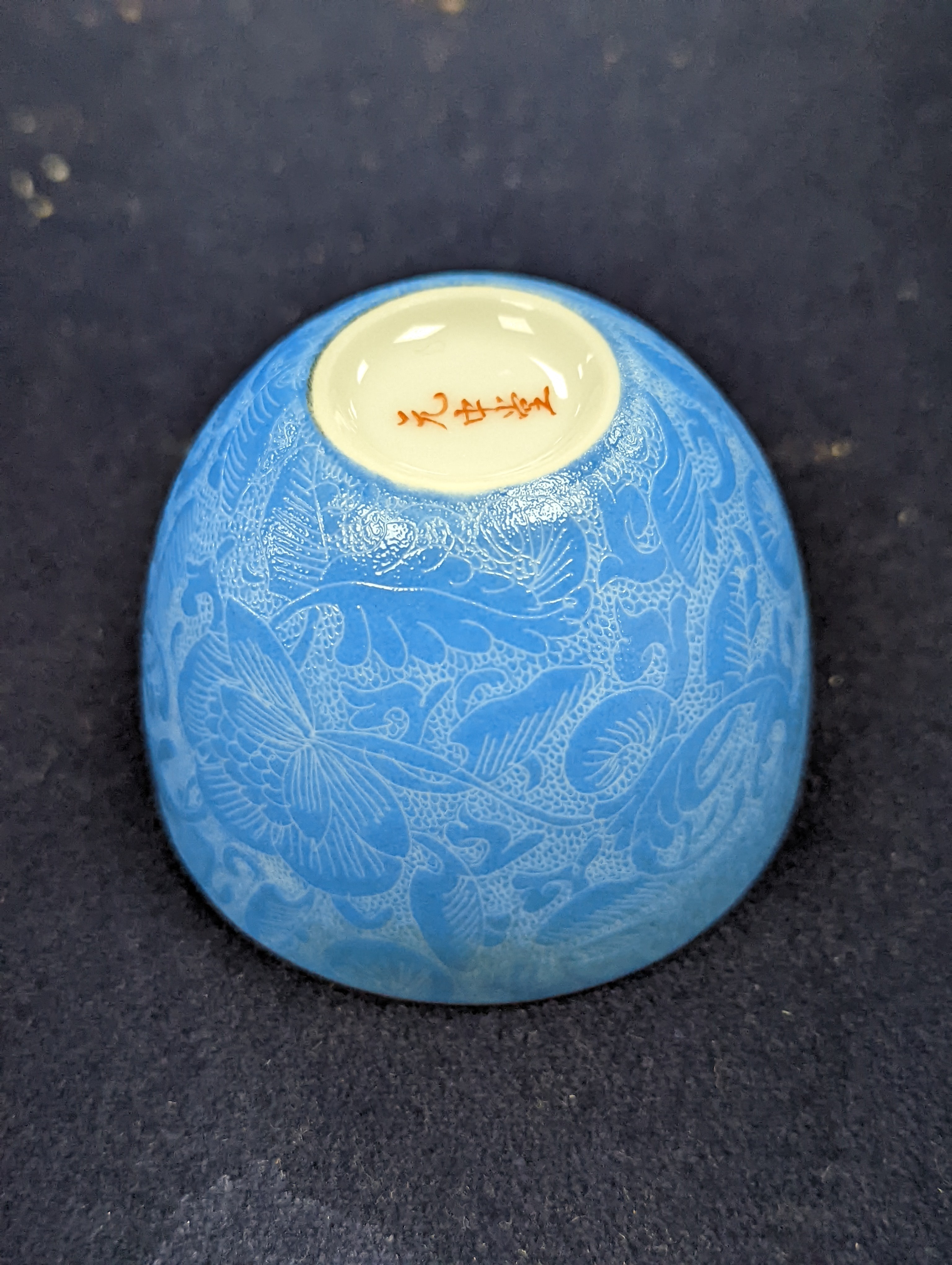 A Japanese or Chinese sgrafitto blue enamelled cup, cased. 6cm diameter